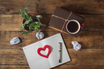Opened Diary and Heart, Flower, Books, Crumpled Paper, Pen on a wooden background
