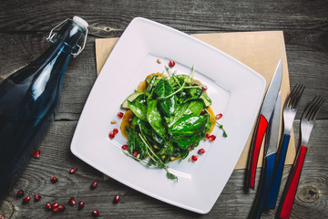 Useful delicious salad of basil, spinach, arugula, watercress salad, grapefruit, olive oil and lemon juice. On a square white plate, on a wooden old table