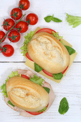 Brötchen Sandwich Baguette belegt mit Käse und Schinken Hochformat von oben auf Holzbrett