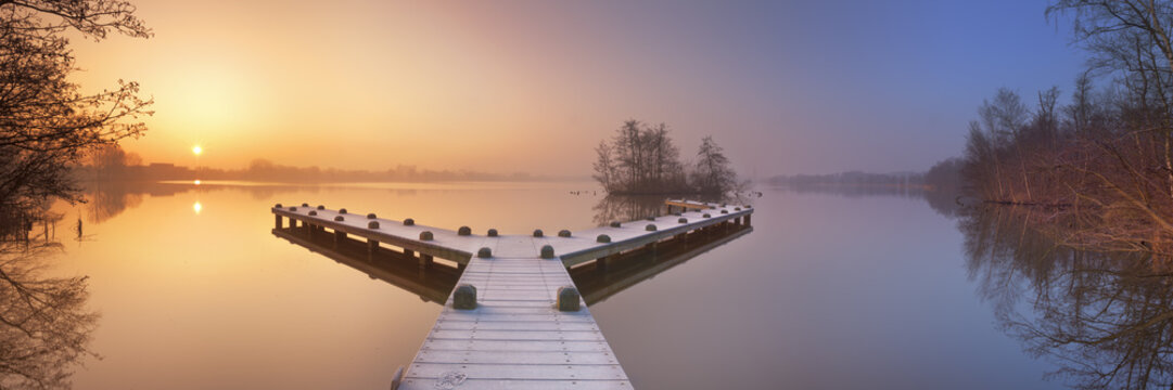 Jetty on a still lake on a foggy winter's morning