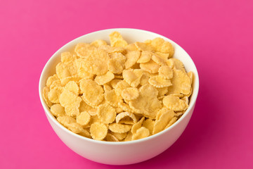 close-up view of white bowl with sweet healthy corn flakes isolated on pink