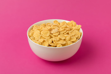 close-up view of white bowl with sweet tasty corn flakes isolated on pink