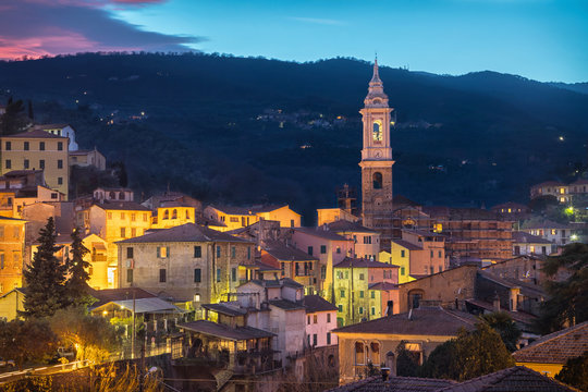 Cityscape of Dolcedo at dusk - small town located in Ligurian Alps, Italy. The main landmark is the bell tower of Church of Saint Thomas (Chiesa di San Tommaso)