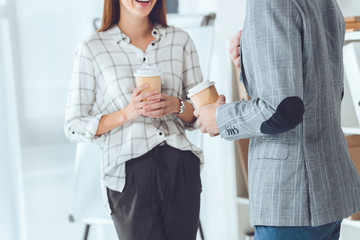 cropped image of male and female colleagues having coffee break in office