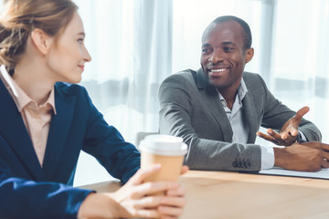 african man smiling to woman with coffe in hands  at office space