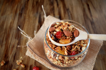 Granola in a glass jar and wooden spoon. Healthy nutrition concept. Rustic style
