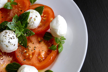 Caprese salad with ripe tomatoes and mozzarella with fresh Basil leaves. Italian food.