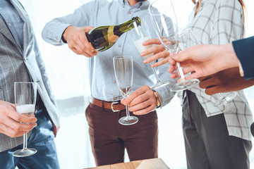 croped image of man in shirt pouring champagne to glasses