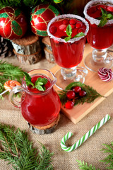 Hot cranberry tea in a glass jug surrounded by Christmas attributes