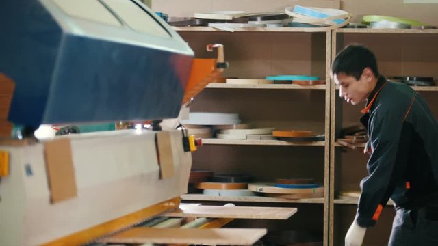 Worker carpenter handles wooden panels on the machine on the furniture factory