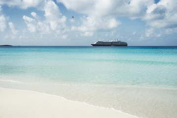 Beautiful sand beach with crystal clear water and cruise ship anchored, Bahamas