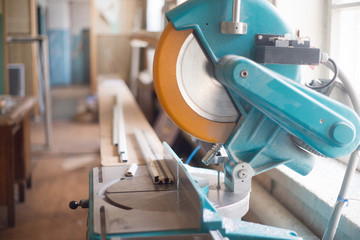 Blue and yellow circular cross-cut electric saw in some industrial background