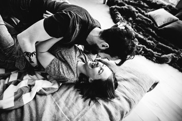 Love story. Man and woman lie in bed, hug each other and laugh. Happiness, couple, morning, bed, top view. Black and white photo