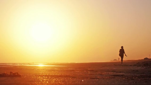 Lonely girl walks along beach at beautiful sunset in slow motion. 1920x1080, hd