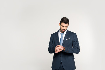 Obraz na płótnie Canvas fashionable young businessman checking wristwatch isolated on grey