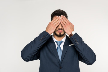 young businessman closing eyes with hands isolated on grey