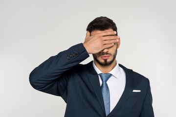 young businessman closing eyes with palm isolated on grey