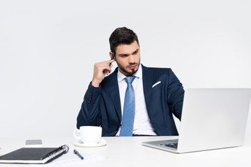 focused young businessman using laptop at workplace on grey