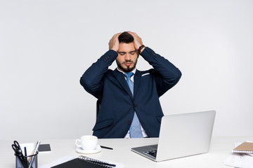 stressed young businessman having headache while sitting at workplace