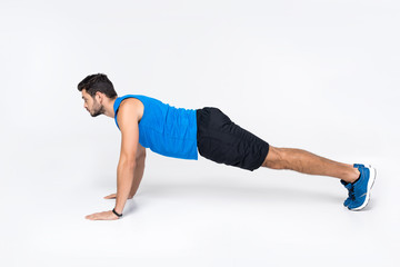 Naklejka premium side view of young man doing push ups on white