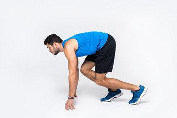 Obraz premium side view of young runner in start position on white