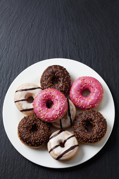 Plate of doughnuts with different icings on slate