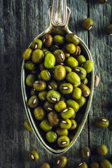 Spoon of mung beans on a wooden background