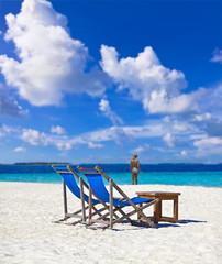 Schöner Maledivenstrand mit Klappliegen und Bikinigirl