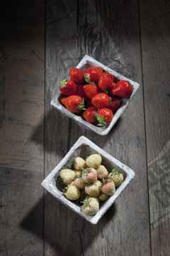 Bowl of pineberries and bowl of strawberries on wood