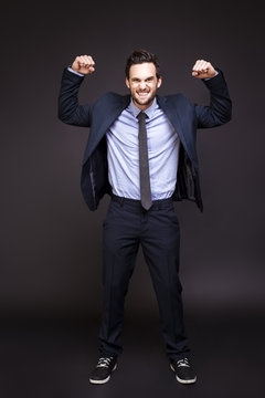 Young man in suit flexing his muscles