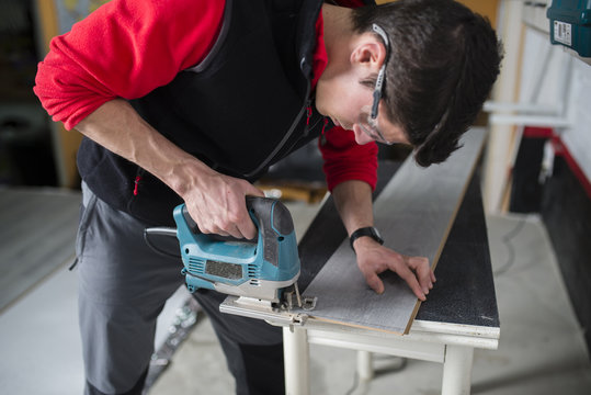 Man cutting laminate floor pieces with a jigsaw