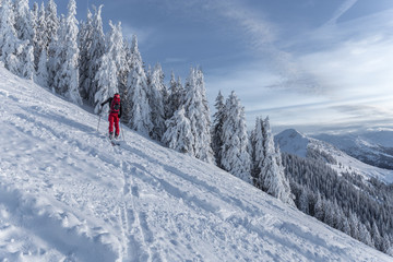 Mann beim Skitouren gehen im Gebirge bei verschneiter Landschaft