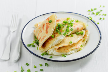 Tasty pancakes with cottage cheese and chive on white table