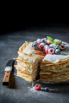 Closeup of stack of pancakes with fresh berries and sugar