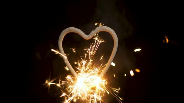 Burning heart shaped sparkler at night 