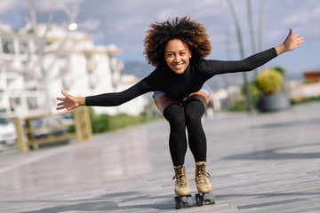 Black woman on roller skates riding outdoors on urban street