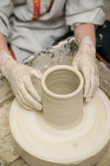 Hands of a potter, creating a pot of clay