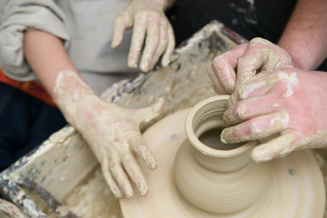 Hands of a potter, creating a pot of clay