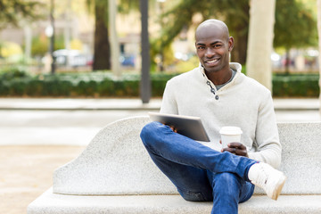 Obraz premium Black young man with tablet computer and take away coffee