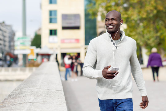 Black young man with a smartphone in his hand in urban background