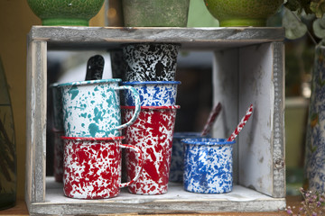 Multicolored cups and glasses on a wooden shelf for sale