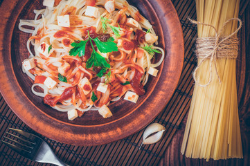 Penne pasta in tomato sauce with chicken, tomatoes decorated with parsley.