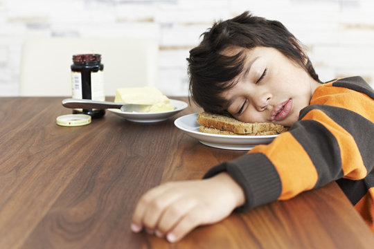 Naklejki Portrait of little boy sleeping at breakfast table