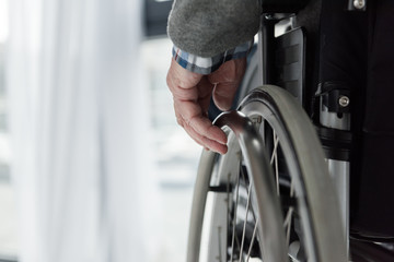 Close-up view of senior man hand on wheel of wheelchair