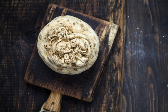 Celeriac on wooden chopping board on dark wood