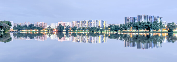 Panorama reflection of new estate HDB housing complex on Jurong Lake neighborhood in Singapore at twilight. Urban concept