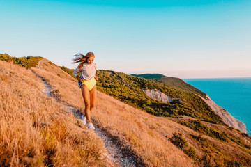 Beautiful sporty woman in nature at warm sunset. Happy girl on a walk in the mountains