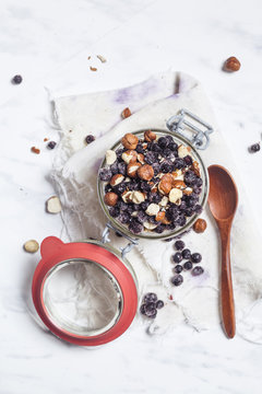 Preserving jar of overnight oats with pineapple, coconut, chia pudding, hazelnuts and berries