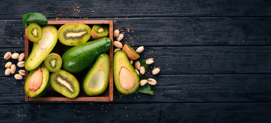 Kiwi and avocado in a wooden basket. On a wooden background. Top view. Free space for your text.