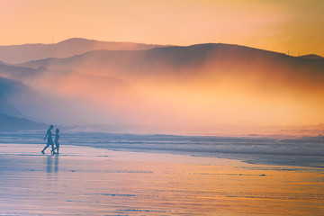 couple walking on beach at sunset